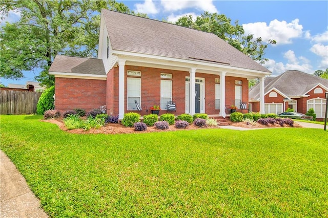 view of front facade with fence, a shingled roof, a front lawn, brick siding, and covered porch