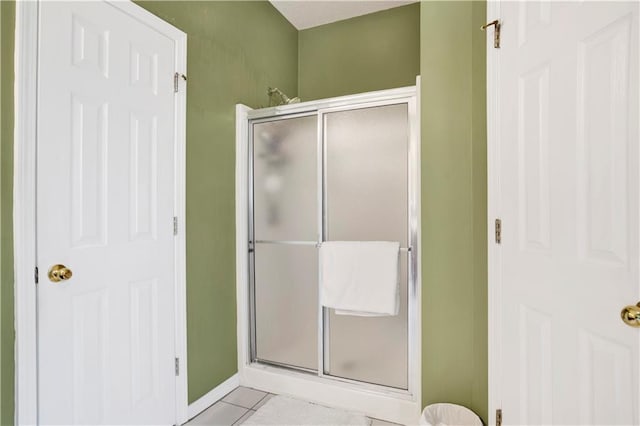bathroom with baseboards, tile patterned floors, and a shower stall