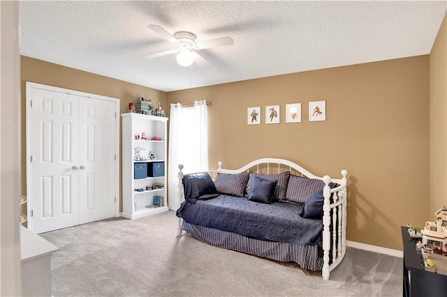bedroom with a ceiling fan, a textured ceiling, carpet floors, baseboards, and a closet