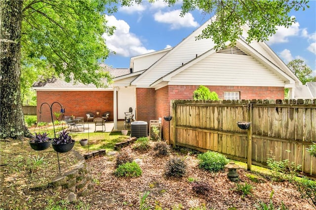 back of house featuring fence, a patio, cooling unit, and brick siding