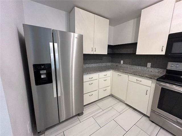 kitchen featuring dark stone countertops, stainless steel appliances, tasteful backsplash, and white cabinets