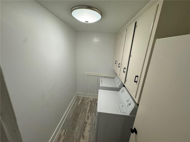 clothes washing area with dark wood-type flooring, washer and dryer, and cabinets