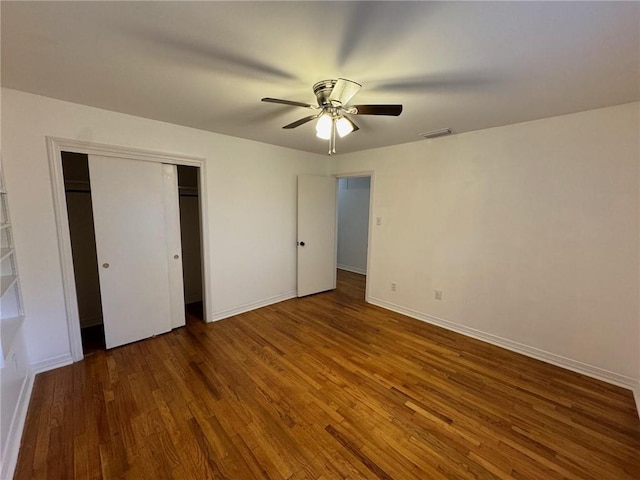 unfurnished bedroom with dark hardwood / wood-style flooring, a closet, and ceiling fan