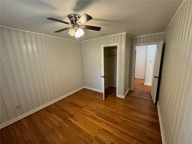 unfurnished bedroom with hardwood / wood-style floors, crown molding, a closet, and ceiling fan