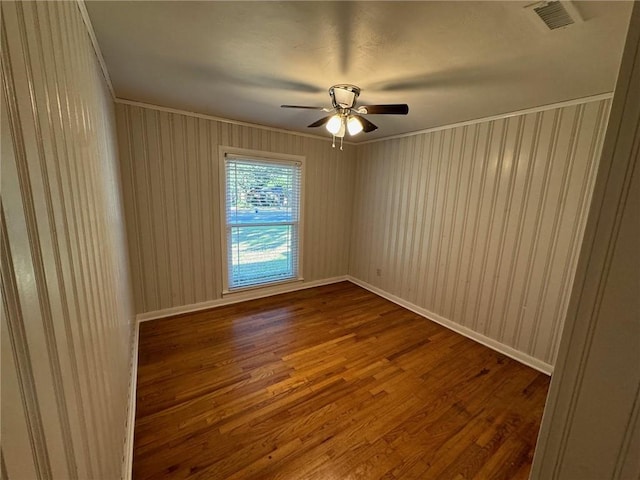 empty room featuring crown molding, wood-type flooring, and ceiling fan