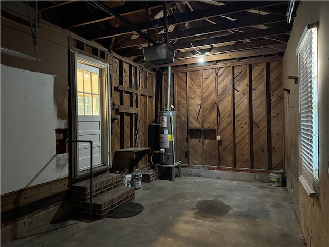 basement featuring water heater and wooden walls