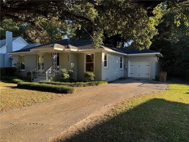 ranch-style home featuring covered porch, a front lawn, and a garage