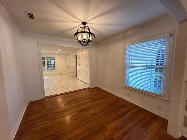 unfurnished dining area featuring a notable chandelier and hardwood / wood-style floors