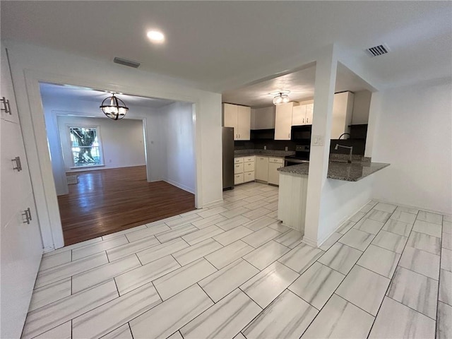 kitchen with kitchen peninsula, pendant lighting, black electric range, white cabinetry, and stainless steel refrigerator