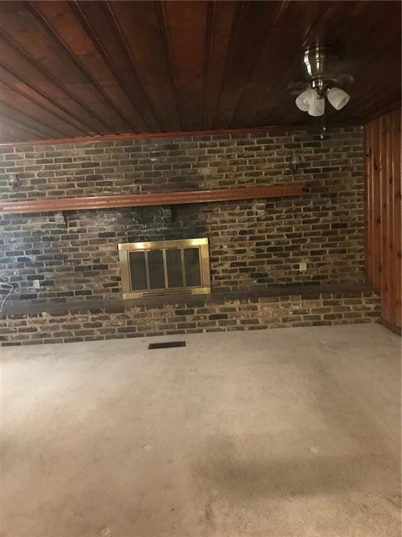 unfurnished living room featuring brick wall, wooden ceiling, and a brick fireplace