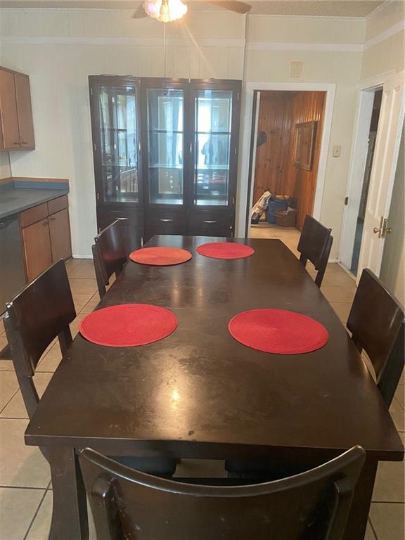 tiled dining room with ceiling fan and ornamental molding