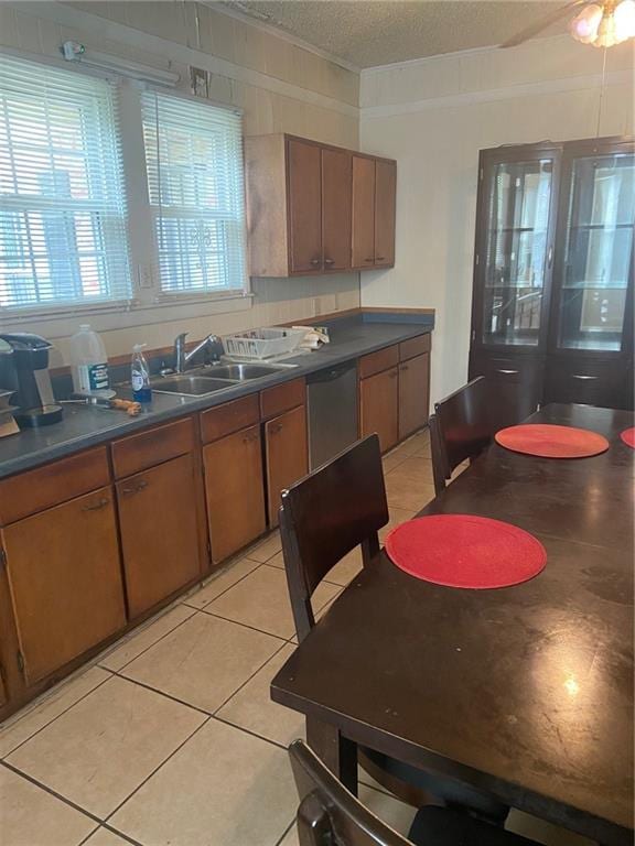 kitchen with a textured ceiling, stainless steel dishwasher, sink, and light tile patterned floors