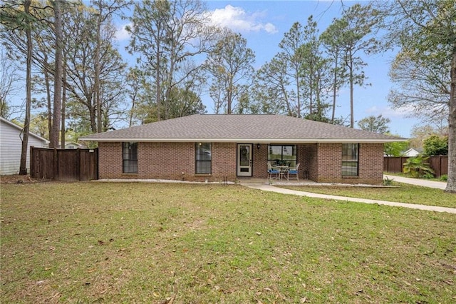 ranch-style house with brick siding, a shingled roof, fence, a front yard, and a patio area