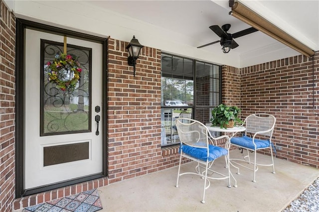 view of exterior entry with a ceiling fan and brick siding