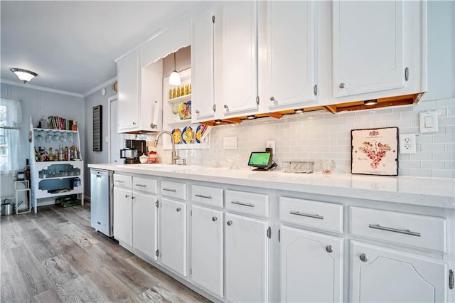 kitchen with sink, crown molding, stainless steel dishwasher, white cabinets, and backsplash