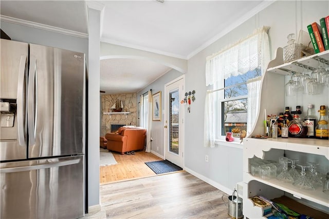 interior space featuring a fireplace, wood-type flooring, ornamental molding, and indoor bar