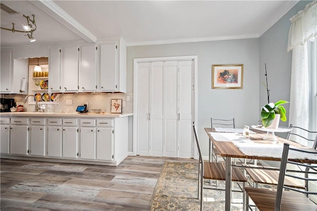 kitchen featuring white cabinetry, crown molding, decorative backsplash, and light hardwood / wood-style flooring