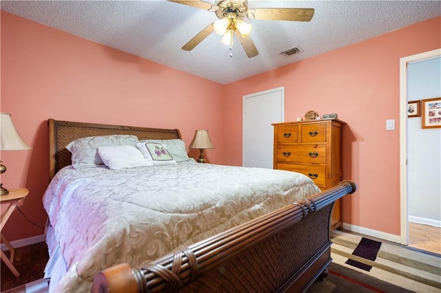 bedroom featuring ceiling fan, hardwood / wood-style floors, and a textured ceiling