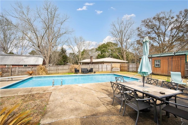 view of swimming pool with a patio, a diving board, and a shed