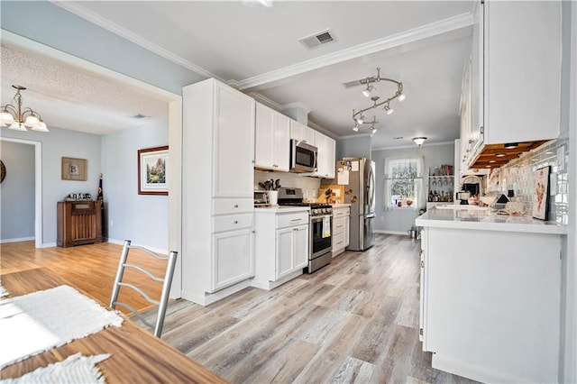 kitchen with stainless steel appliances, tasteful backsplash, hanging light fixtures, and white cabinets