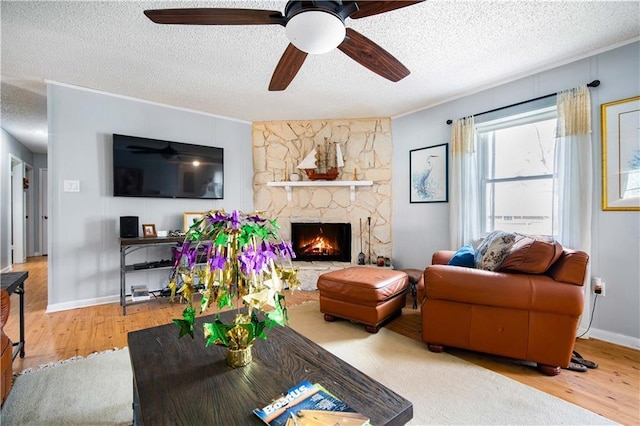 living room with wood-type flooring, a stone fireplace, crown molding, and a textured ceiling