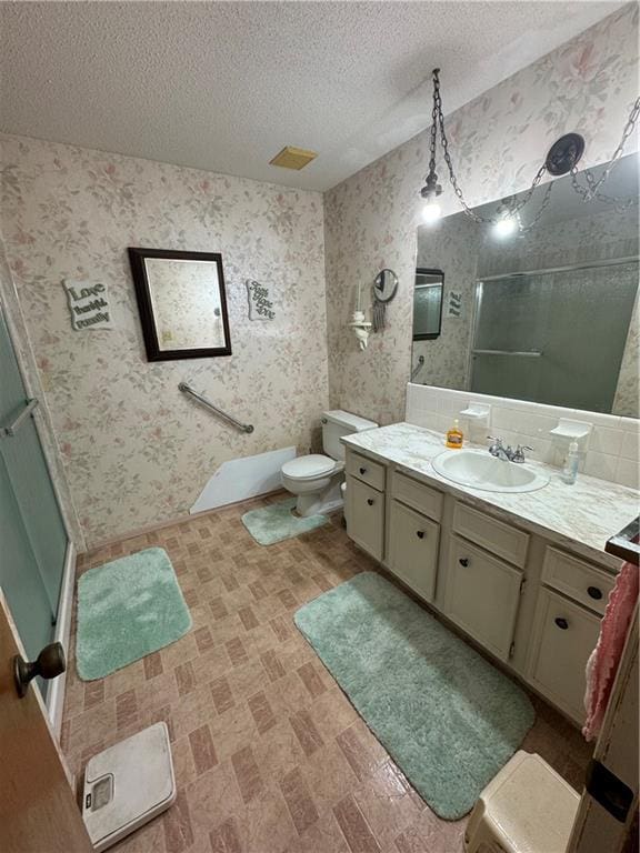 bathroom with vanity, toilet, a textured ceiling, and walk in shower