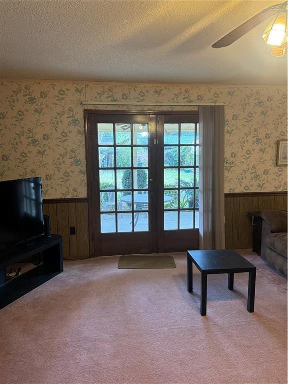 carpeted living room with a textured ceiling, ceiling fan, and french doors