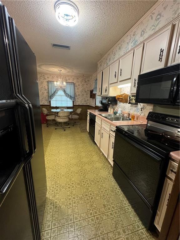 kitchen with sink, white cabinetry, a textured ceiling, a notable chandelier, and black appliances