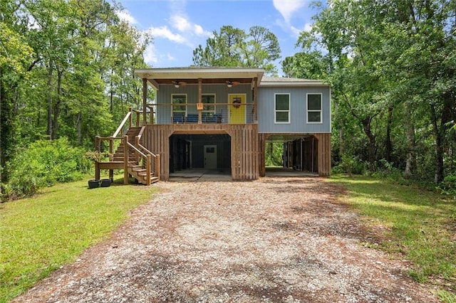 911 Lockenbie Pl, Dauphin Island, AL 36528 - coastal inspired home featuring a ceiling fan, a carport, dirt driveway, stairway, and a front lawn
