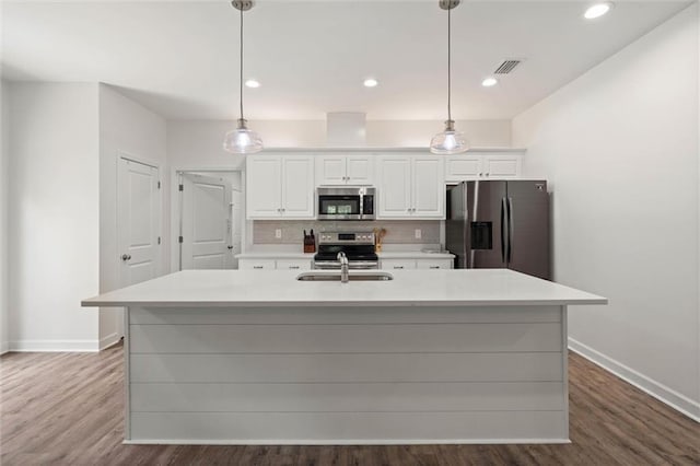 911 Lockenbie Pl, Dauphin Island, AL 36528 - kitchen with stainless steel appliances, white cabinets, backsplash, light countertops, and a center island with sink