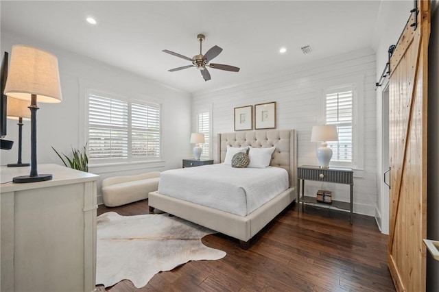 bedroom featuring a barn door, recessed lighting, visible vents, and dark wood-style flooring