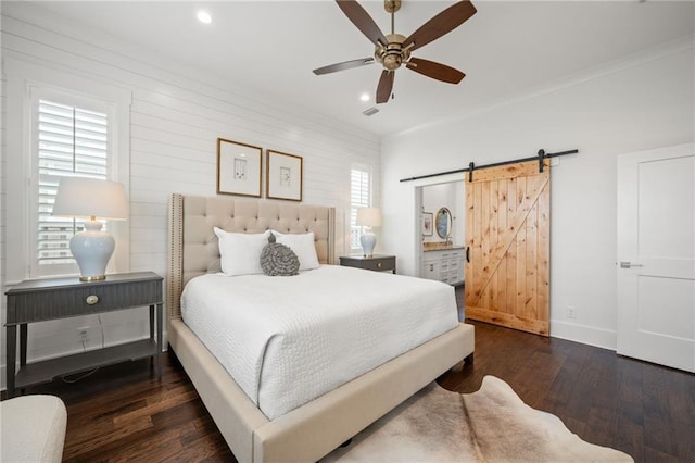 bedroom with wood finished floors, baseboards, visible vents, recessed lighting, and a barn door