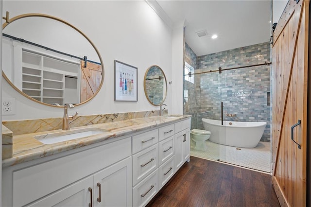 full bathroom with a freestanding bath, double vanity, wood finished floors, and a sink