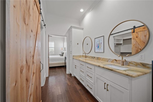 full bath featuring crown molding, double vanity, ensuite bathroom, wood finished floors, and a sink