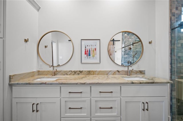 full bath featuring a sink, a shower with door, and double vanity