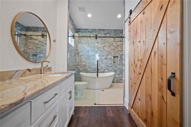 full bathroom featuring a freestanding tub, visible vents, wood finished floors, tile walls, and vanity