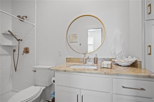 bathroom featuring toilet, vanity, and a tile shower