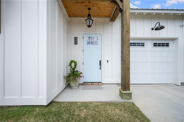 doorway to property with a garage, board and batten siding, and concrete driveway