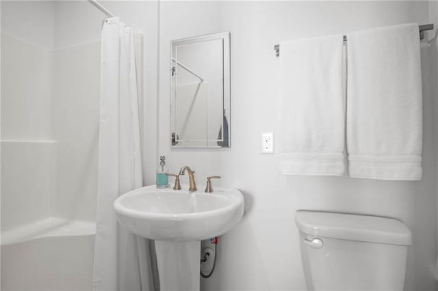 bathroom featuring a shower with shower curtain, toilet, and a sink