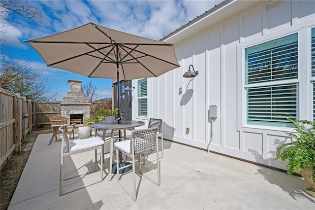 view of patio featuring an outdoor stone fireplace, a fenced backyard, and outdoor dining space