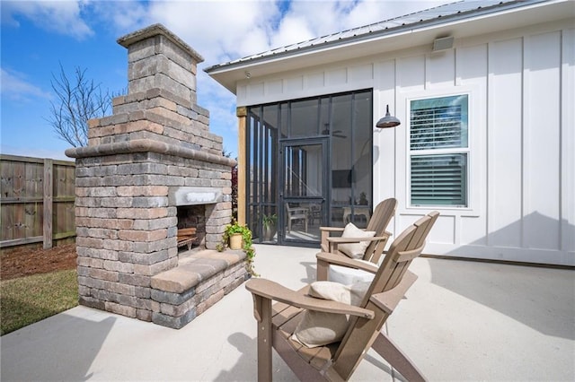 view of patio featuring an outdoor fireplace and fence