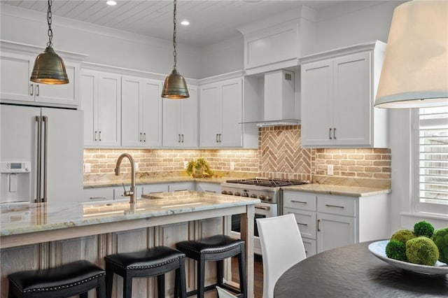 kitchen featuring high quality appliances, decorative backsplash, white cabinets, a kitchen breakfast bar, and wall chimney exhaust hood