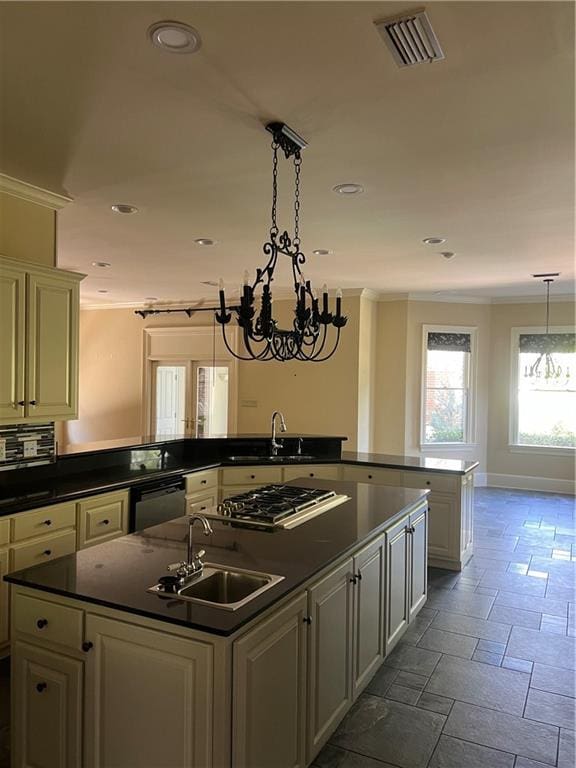 kitchen with dark countertops, visible vents, a kitchen island with sink, stainless steel gas stovetop, and a sink