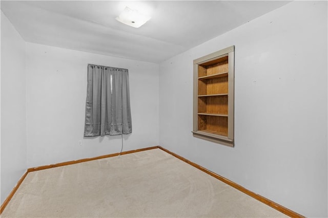 carpeted spare room featuring built in features