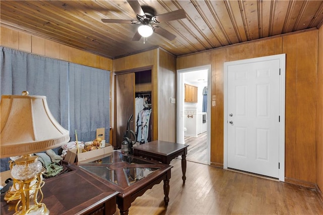 interior space with wood-type flooring, ceiling fan, wood ceiling, and wood walls