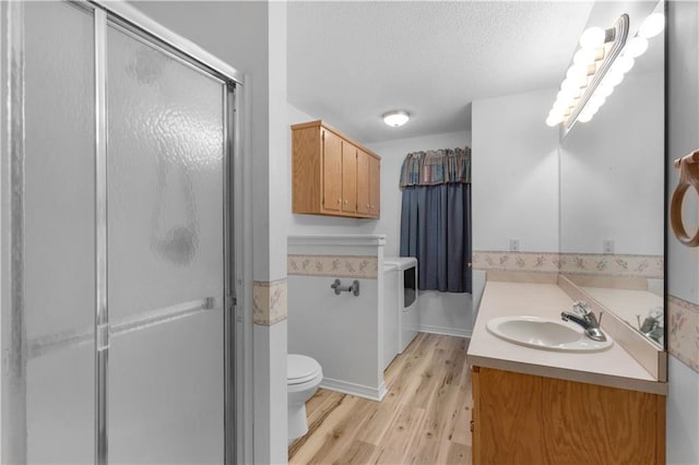 bathroom with a shower with shower door, wood-type flooring, vanity, toilet, and a textured ceiling