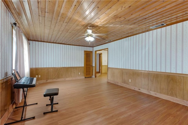 workout area featuring hardwood / wood-style flooring, ceiling fan, wood ceiling, and wooden walls