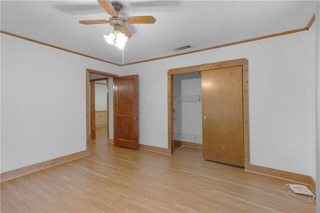 unfurnished bedroom with crown molding, light hardwood / wood-style flooring, a closet, and ceiling fan