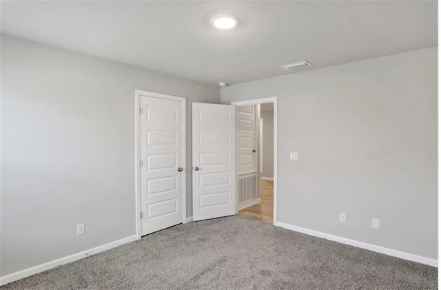 unfurnished bedroom featuring carpet, visible vents, and baseboards