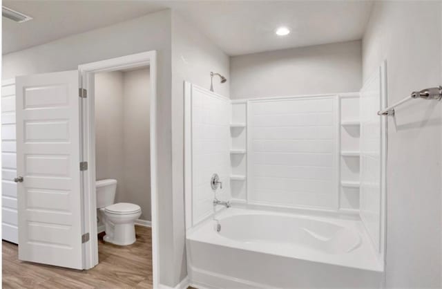 bathroom with bathing tub / shower combination, wood finished floors, toilet, and baseboards